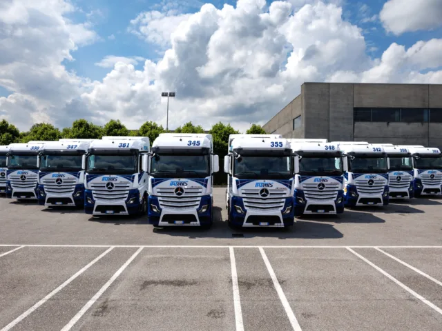 Visione frontale della flotta di trattori Italtrans Mercedes-Benz Actros L parcheggiati e disposti a piramide.